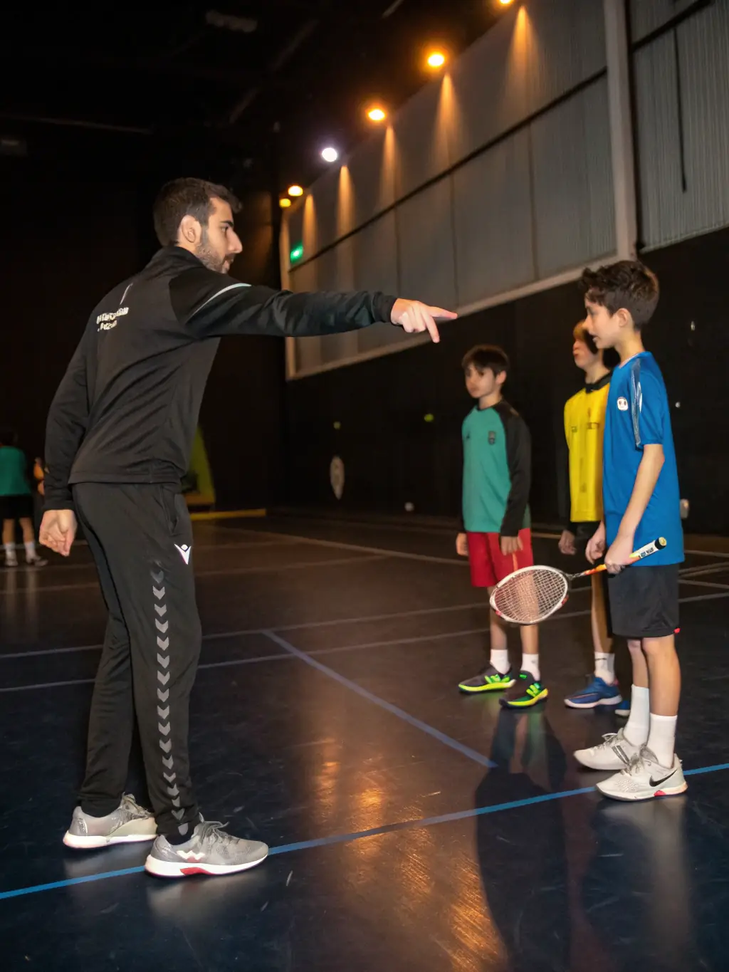 A coach demonstrating table tennis techniques to a group of players during a training session at ETREUX TENNIS DE TABLE (E.T.T.).